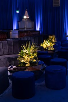 the tables are decorated with flowers and blue velvet stools in front of large drapes