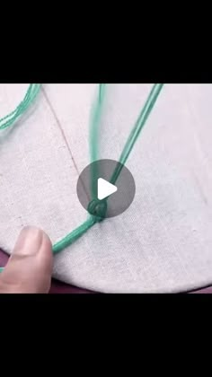 someone is stitching something on the side of a piece of cloth with green thread