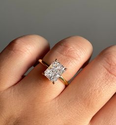 a woman's hand with a diamond ring on top of her finger, showing the center stone