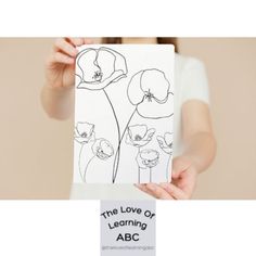 a woman holding up a card with an image of flowers on it that reads the love of learning abc