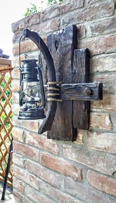 an old lantern hanging on the side of a brick wall next to a wooden fence