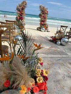 flowers and chairs on the beach with people in the water