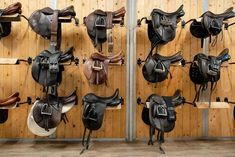 several different types of saddles hanging on the wall