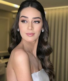 a woman with long dark hair is posing for a photo in a white strapless dress