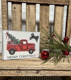 a red truck with a christmas tree painted on the back is sitting on a wooden bench