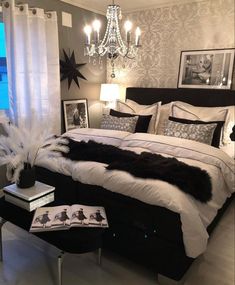 a black and white bedroom with chandelier, bedding, pillows and pictures on the wall