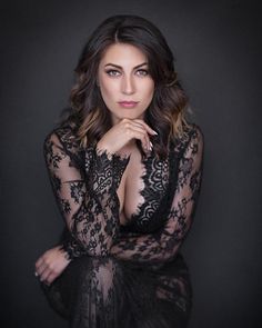 a beautiful woman in black lacy clothing posing for a photo with her hands on her chin