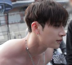 a shirtless young man with piercings on his neck and chest is looking at something in the distance