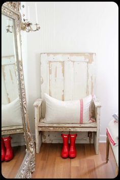 a wooden bench sitting next to a mirror on top of a hard wood floor in front of a white wall