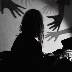 a person sitting in front of a wall with shadows on it