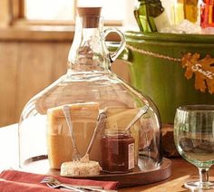 a table topped with wine glasses and bottles filled with different types of cheese, jams and crackers