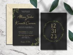 an elegant black and gold wedding card with greenery on the front, featuring a wreath