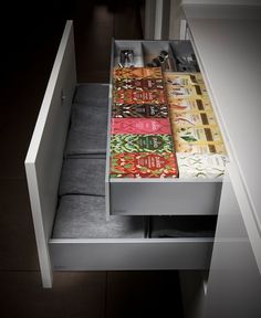 an open drawer in a kitchen with towels and utensils on the bottom shelf