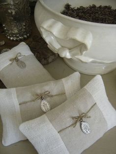 three linen pillows tied with twine and sitting on a table next to a bowl