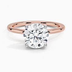 a rose gold engagement ring with a round cut diamond in the center, on a white background