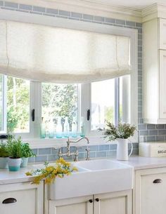 a kitchen window with roman shades over the sink and windows above it are decorated with flowers