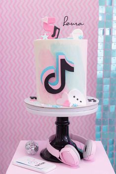 a pink and blue cake with headphones on a white pedestal in front of a pink wall