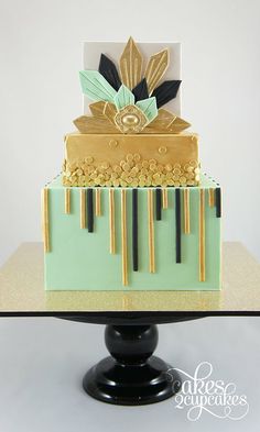 a three tiered cake with gold and black decorations on the top, sitting on a pedestal