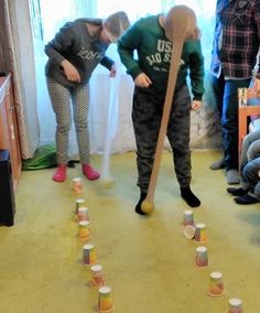 two children are playing with cups and a broom in the living room while others watch