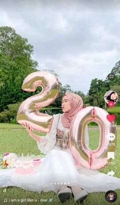 a woman sitting in the grass with balloons that spell out the number twenty two on it