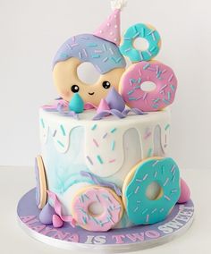 a birthday cake decorated with donuts and sprinkles for a child's first birthday