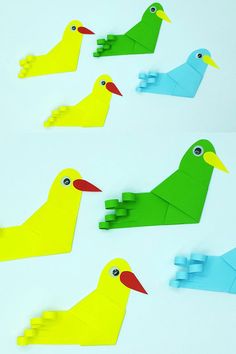 four birds made out of paper sitting on top of a white table next to each other