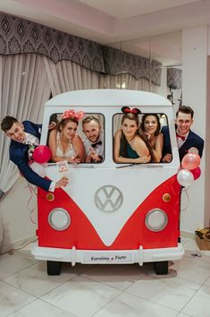 a group of people standing in front of a vw bus with balloons and streamers