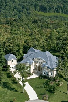 an aerial view of a large house in the middle of a wooded area with lots of trees