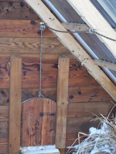 an old chair hanging from the side of a wooden building with snow on the ground