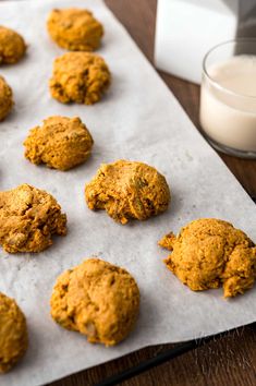 some cookies are sitting on a baking sheet next to a glass of milk and a napkin