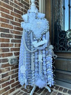 a mannequin made out of blue and white feathers on a brick wall next to a door