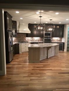 an empty kitchen with wooden floors and dark cabinets