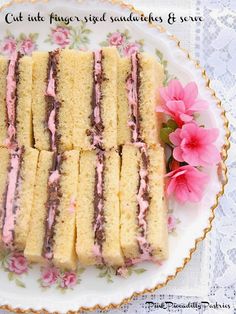 a white plate topped with cut in half sandwiches next to a pink flower on top of a table