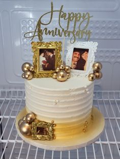 a white cake with gold decorations and two pictures on top, sitting on a rack