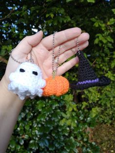 a hand holding two small knitted items in the shape of sheep and pumpkins