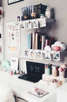 a white desk topped with a laptop computer next to a shelf filled with pictures and other items