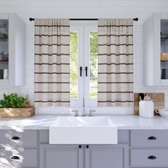 a kitchen sink sitting under a window next to a counter top with a cutting board on it