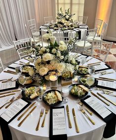 the table is set with gold and white flowers, silverware, and menus