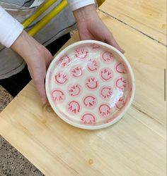 a person is holding a bowl with red designs on it and another hand holds the bowl