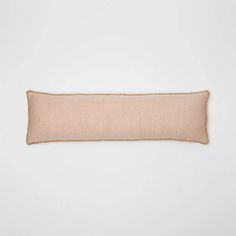 a beige pillow sitting on top of a white wall