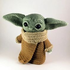 a crocheted baby yoda doll is posed on a white background