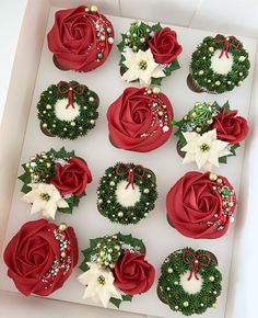 twelve cupcakes in a box decorated with red roses and green wreaths on them