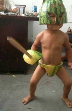 a young boy wearing a watermelon hat and holding a banana in his hand