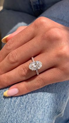 a woman's hand with yellow nails and a ring on her finger, wearing jeans