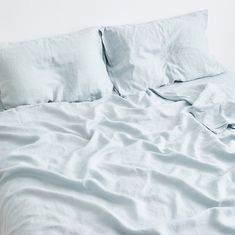 an unmade bed with white sheets and pillows