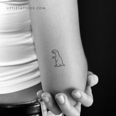 a woman's arm with a small dinosaur tattoo on the left side of her arm