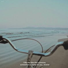 a bike is parked on the beach near the water and sand with an inspirational quote