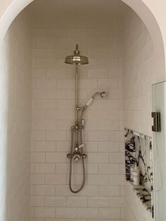 a bathroom with a shower head and white tile walls