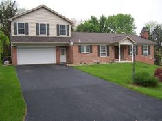 a house with a driveway in front of it and grass on the other side of the street