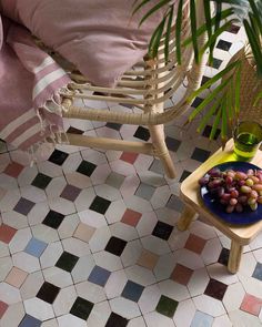 a table topped with grapes on top of a tiled floor next to a potted plant